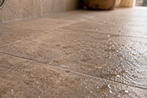 Gros plan de carrelage de sol antidérapant avec surface texturée et gouttes d'eau, effet pierre naturelle. Illustration de l'importance de l'antidérapance pour le carrelage de salle de bain