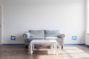 Comment préparer une pièce avant de peindre : protection des prises, pose du ruban de masquage sur les plinthes et bâchage des meubles